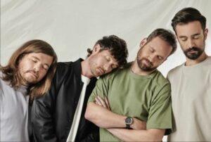 Bastille pretending to sleep on each other's shoulders in press shot.